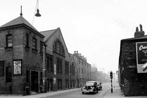 A view looking west along Sheepscar Street North from the junction with Barrack Street shows Sheepscar Congregational Chapel on the left. Two cars drive past a traffic light. Pictured in October 1946.