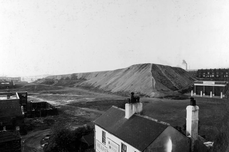 The Pit Hills on York Road pictured in September 1938. Buildings to left, pit hills in the foreground. At the foot of the picture is 'John William Heaps' - a two storey building with the sign on the front saying 'Heaps Motor Booking Office'