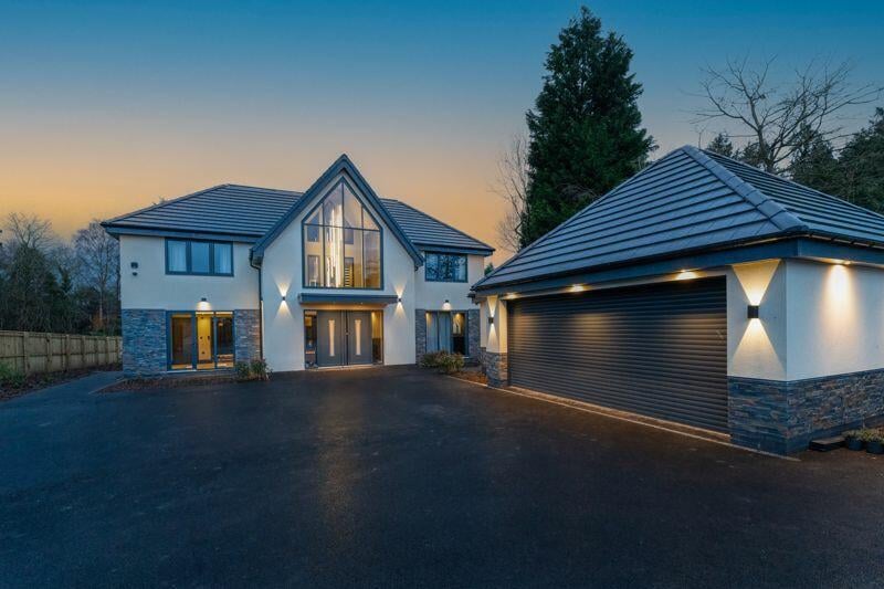 The property is accessed by secure electronic gates, which open to an extensive driveway with a separate garage.
