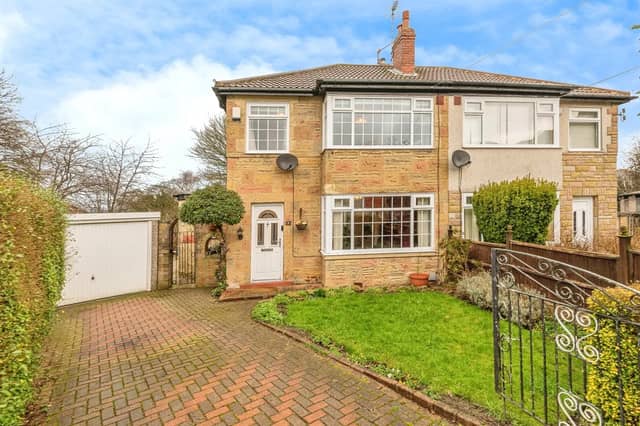 To the front of this three-bedroom home is a small lawned garden and a large driveway leading to a garage.