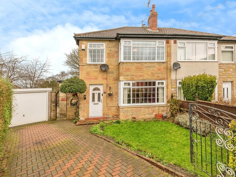 To the front of this three-bedroom home is a small lawned garden and a large driveway leading to a garage.