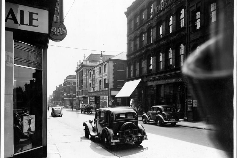 Albion Street in August 1939. This view is looking towards Boar Lane, across The Headrow. On the left side is the  corner of Standard Cars showroom. On right number 127 Charles Whitelock, tailor Number 125, St Ann's Buildings housed Hillman Brothers wireless factors, Leeds Premier Supply Co. Clothing club, Miss Lizzie Crosby artist, Loyal Order of Ancient Shepherds Friendly Society. At the top of the building, sign 'Hearts of Oak' Assurance Co. Ltd. Number 123 S.N. Kilner jeweller has shop blind down to protect window. Next, junction with Coronation Place. 119 Miller Page Furnishing.  