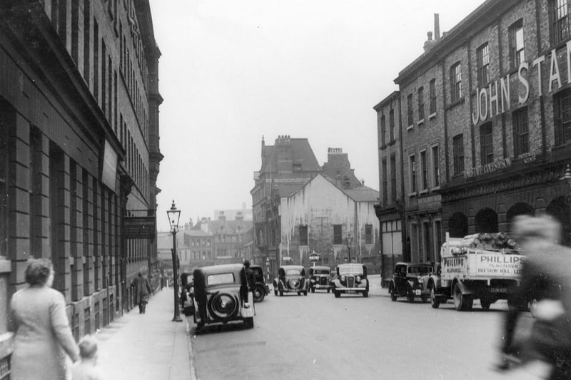 Traffic on Great George Street. Pedestrians and streetlamps are visible. The Leeds Education Dept. is on the left. Pictured in July 1939.