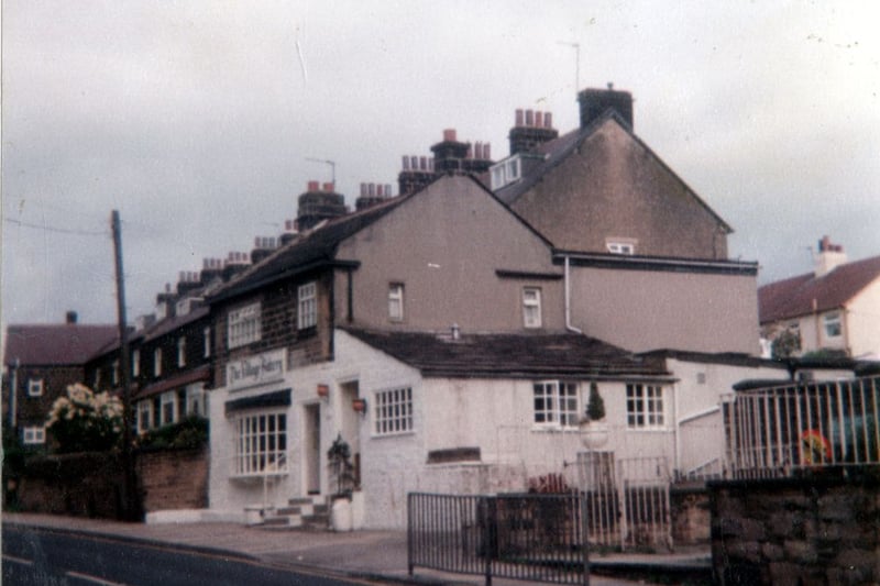 The white painted building in the centre is the Village Bakery. On the right is entrance to St. Peter's Junior and Infant School.