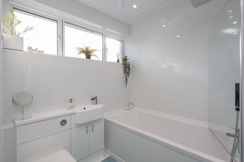 The contemporary family bathroom, with white three-piece suite comprising WC, wash hand basin and bath with shower over.