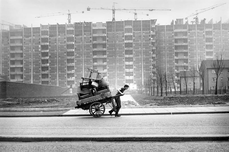 A man pulling a barra past tower blocks under construction in the Gorbals. The tenements which had formerly occupied the site were among the worst slums in Britain and there had been campaigns to redevelop the area for many years before work finally began in the late fifties.