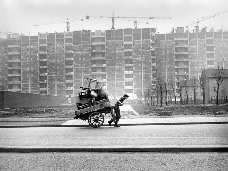 A man pulling a barra past tower blocks under construction in the Gorbals. The tenements which had formerly occupied the site were among the worst slums in Britain and there had been campaigns to redevelop the area for many years before work finally began in the late fifties.