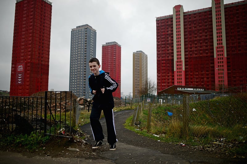 A child runs down the path to play while the Red Road flats are prepped for demolition in the background.