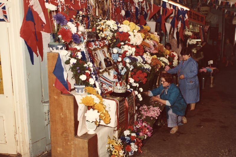 A view of the interior of the Grainger Market Newcastle upon Tyne taken in 1977. The photograph shows one of the flower stalls which is decorated with bunting flowers and photographs for the Silver Jubilee of Queen Elizabeth II.