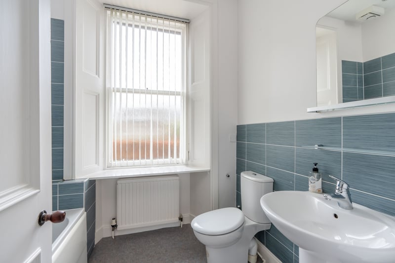The family bathroom with modern three-piece white suite and tiling to splash areas.