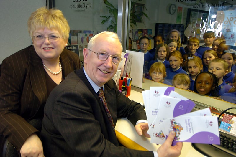 Leeds East MP George Mudie and Susan Davenport, chief executive-Leeds City Credit Union, behind the counter at the opening of the new Leeds City Credit Union branch at Seacroft South One Stop Centre in March 2006. Looking on are children from Seacroft Grange Primary choir who entertained at the opening ceremony.