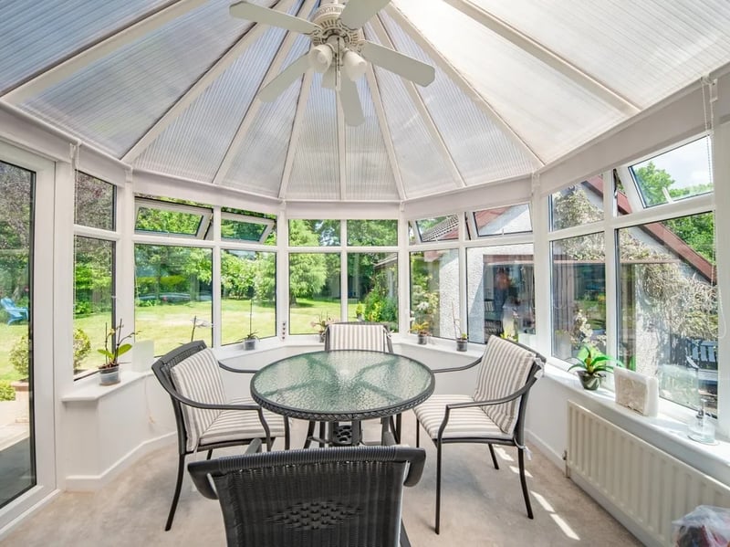 The kitchen leads directly into this conservatory room, which looks to be the current main dining space.