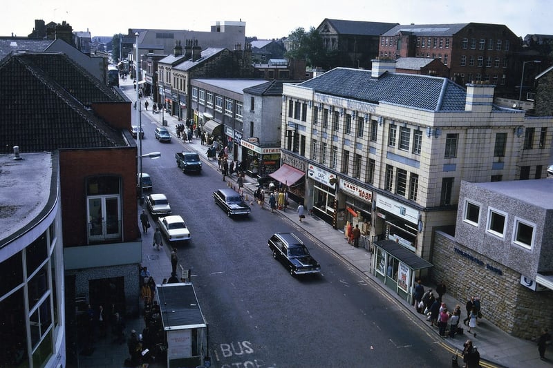 Looking south along Queen Street from the turret on the former Morley Co-op 1899 building in August 1973. On the left hand side part of Society House and the 1937 red brick Emporium can be seen. On the street there is a hearse with one following car while on the right hand side is the Yorkshire Bank then the Town Hall Buildings which include the Town Hall Barbers, the Handyman's Shop, The Town Hall Cafe (Kennedy's) and Albert Webster's butchers shop.