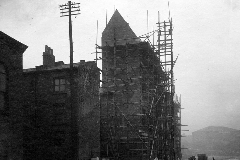 building under construction, surrounded by scaffolding. The pavement and road are unmade. In the background can be seen Scarr's warehouse at the bottom of The Headrow, near St. Peter's Street. Pictured in September 1931. 