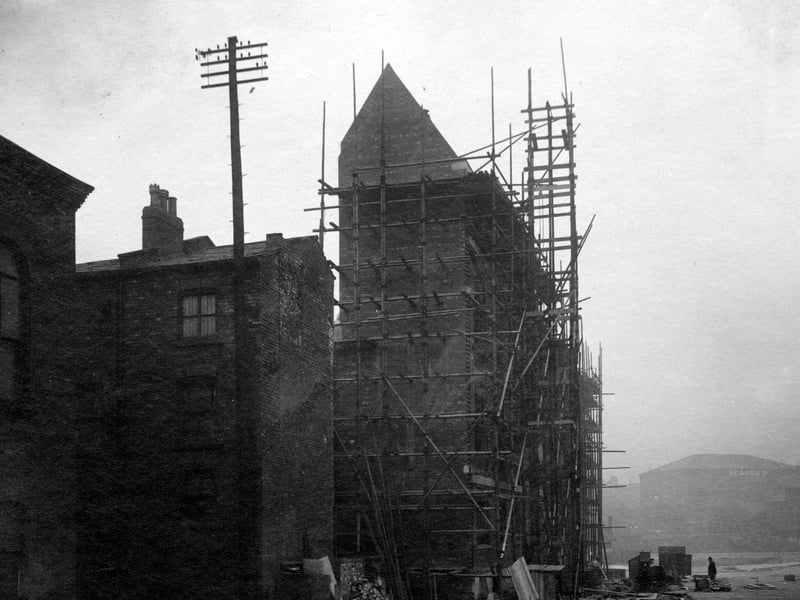 building under construction, surrounded by scaffolding. The pavement and road are unmade. In the background can be seen Scarr's warehouse at the bottom of The Headrow, near St. Peter's Street. Pictured in September 1931. 