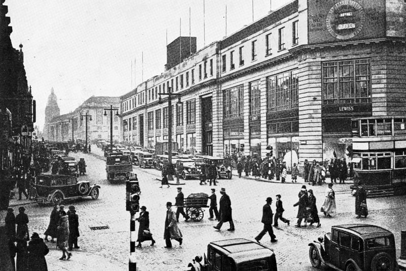 The Headrow at the junction with Briggate looking West to the Town Hall in the background pictured in 1933. At this time a scheme to redevelop and widen The Headrow had just been completed. The new Lewis's store is on the right. Work began on site in 1930 and the store, designed by Atkinson and Shaw, opened on 17th September 1932. Further floors were added before it was fully completed in 1938.