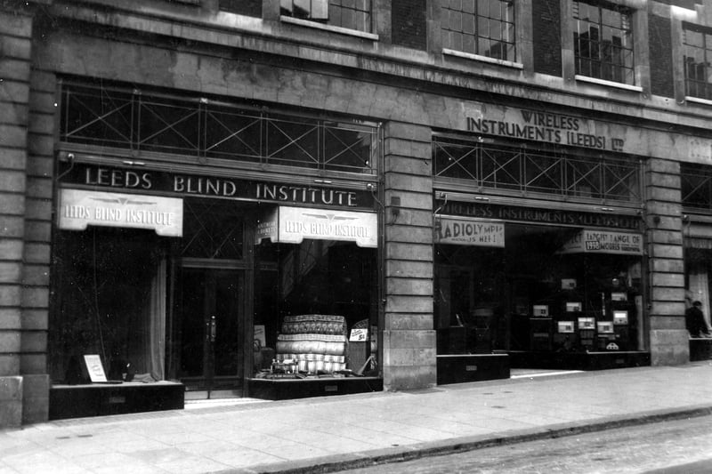 Number 58 shop for Leeds Blind Institute selling goods made by Leeds workshops for Blind. Numbers 54/56 Wireless Instruments Leeds Ltd, Wireless dealers. Pictured in September 1937.