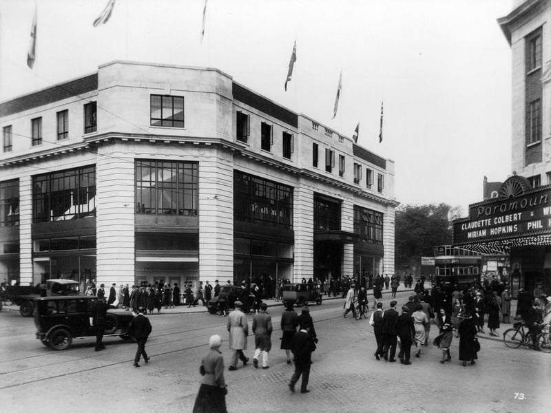 The Headrow at the junction with New Briggate, showing Lewis's department store on the left, possibly at the time of its opening on September 17, 1932 as the streets are lined with people and flags decorate the top of the store. On the right is the Paramount Cinema, later The Odeon, with films starring Claudette Colbert and Miriam Hopkins the main attraction.