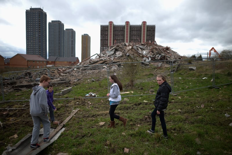 A group of children walk past the thirty story tower block at Birnie Court after it was demolished, in May 2013.  