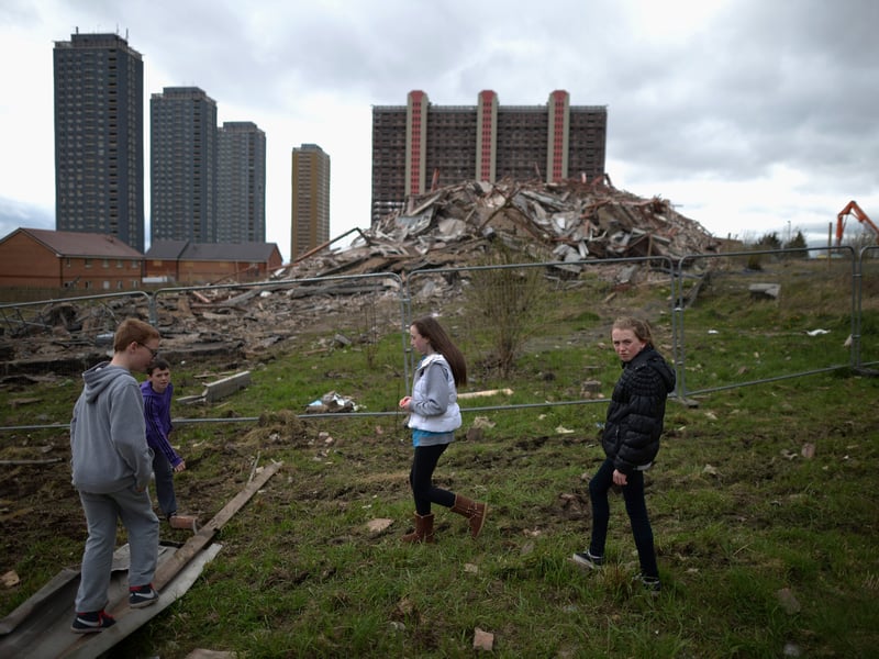 A group of children walk past the thirty story tower block at Birnie Court after it was demolished, in May 2013.  