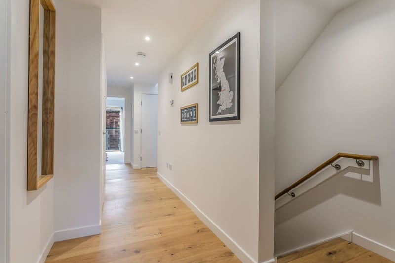 A set of external steps leads to the apartment's front door, where a hallway (with built-in storage) welcomes you inside, setting the tone for the interiors to follow with neutral décor and warm wood-styled flooring.