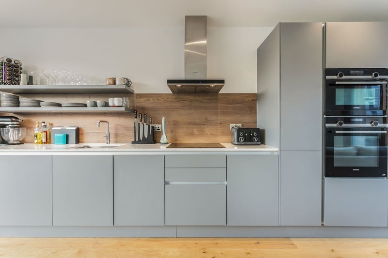 The kitchen is neatly fitted to one wall and comprises contemporary grey-toned cabinetry, gleaming Silestone worktops, and splashback panels. A spacious utility/ laundry room on the first floor supplements the kitchen, offering additional cabinetry and workspace, as well as space for laundry appliances.