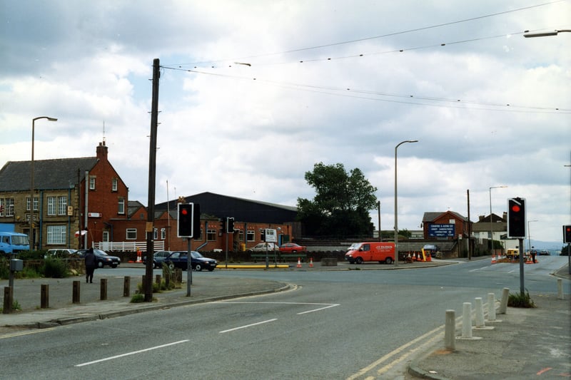Looking from Bruntcliffe Lane onto the junction with Bruntcliffe Road to the left, Howden Clough Road ahead and Wakefield Road to the right. On the left is the Bruntcliffe Working Men's Club; behind this, are the works of Crabtree & Astin Ltd, joinery manufacturers. The white building on the right is the Shoulder of Mutton Inn. Pictured in June 1990.