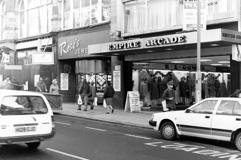 The east side of Briggate showing the entrance to the Empire Arcade in December 1990. This was opened in 1964 on the site of the old Empire Theatre; in 1996 it was redeveloped to become Harvey Nichols. R.L.Gowns, ladieswear, can be seen in the arcade. Next to it at No.107-108 Briggate is Rose's Jewellers, then a shop in the process of being redeveloped.