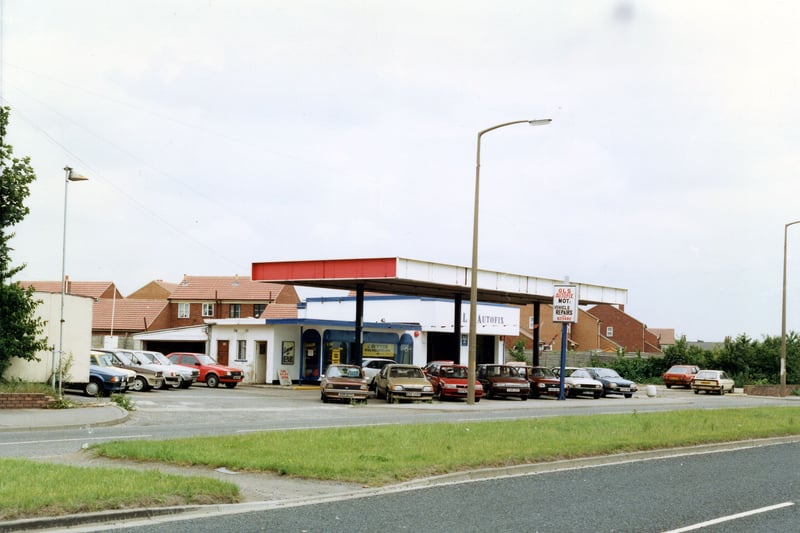 John O'Gaunts Service Station on Leeds Road. Several cars are parked in the forecourt. Houses on Rosewood Court can be seen in the background. Pictured in June 1990.