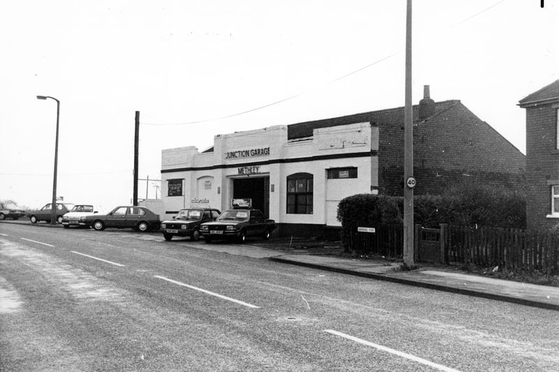 Barnsdale Road showing the Junction Garage in December 1990. Cars for sale are on display outside. The edge of the house at no. 16 can be seen on the right.