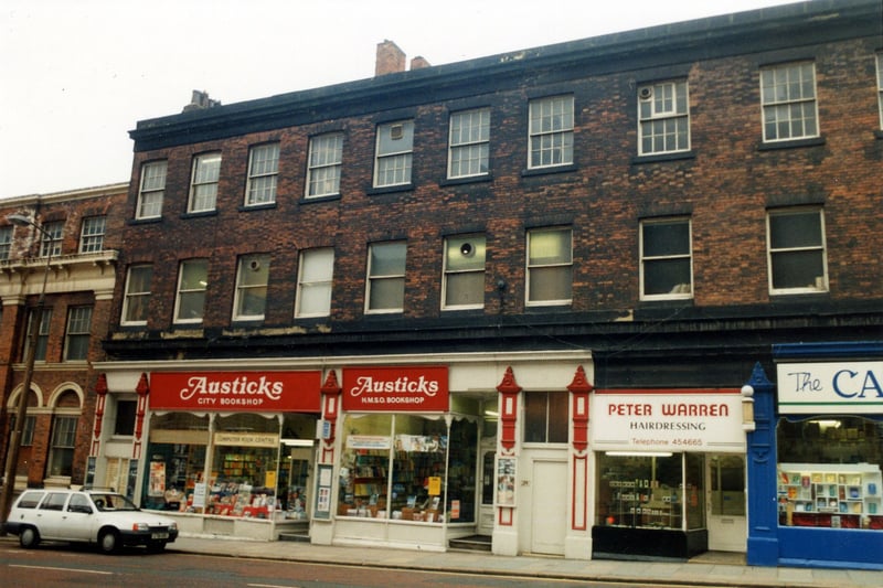 A parade of shops on Cookridge Street with run down offices above in April 1990. At No.27 on the left is Austicks H.M.S.O. Bookshop. At No.29 is the Peter Warren hairdressers. On the far right at No.31 is the Carmel Religious Bookshop. In 1992 this building was redeveloped and opened as shops, offices and a bar.