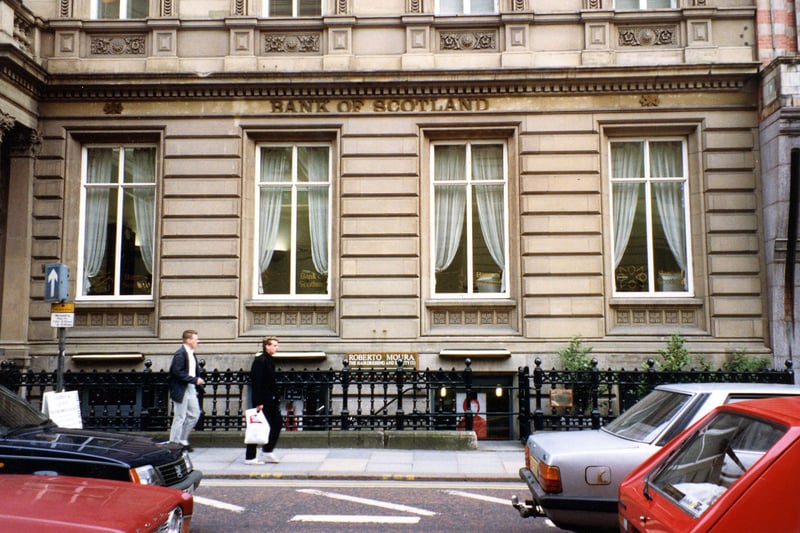 Park Row, showing the Bank of Scotland which occupies nos. 21-22. There are railings outside and steps leading down to Roberto Moura, hairdresser in the basement of the building. Two men are walking past and cars are on the road. Pictured in November 1990.