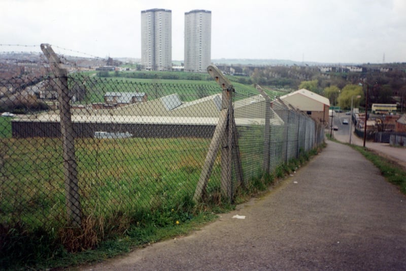 A photo looking west with Crow Nest Lane on the right. Industrial works can be seen in the centre with the tower blocks of Cottingley Towers and Cottingley Heights in the background. Pictured in December 1990.
