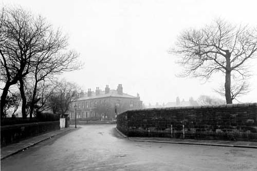 Looking south-east from Church Road, along part of Strawberry Lane towards Hall Lane. The road is bordered by stone walls. The houses of Hall Lane are in the distance, as is a streetlamp. Pictured in December 1947.