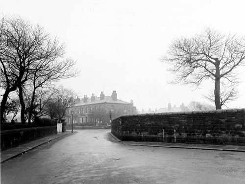 Looking south-east from Church Road, along part of Strawberry Lane towards Hall Lane. The road is bordered by stone walls. The houses of Hall Lane are in the distance, as is a streetlamp. Pictured in December 1947.