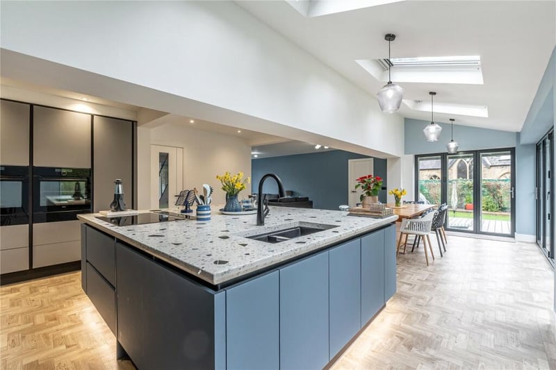 The stunning kitchen has a large central island and a range of units and appliances.