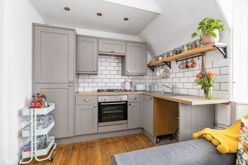  The kitchen is fitted with contemporary wall and base units, wooden worktops, tile splashbacks and a stainless-steel sink. Appliances include an integrated gas hob and electric oven, with space for a free-standing washing machine.
