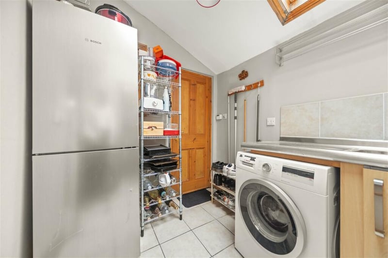 Behind the kitchen is a handy utility room with American style fridge freezer.