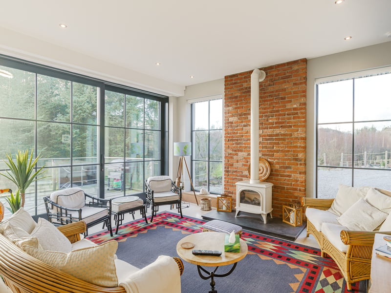 Full-height south-facing sliding doors by Mozolowski & Murray provide wonderful views over the grounds and loch while a wood-burning stove ensures the space is cosy during the winter months.
