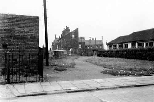 Part of a series taken above ground for Middleton Outfall Sewer in August 1953. Looking north-north-east from Derbyshire Street. On the right the side of Hunslet Nursery; to the left an electricity sub station. Between these, a telegraph pole and wall bordering a track with grass and hedge to the side of the nursery. A boy is playing on a second pole, with a girl standing next to him. Behind the wall is the front three-quarter view of a terrace of houses on Iveridge Street. Further houses are to the right and behind these, on Iveridge Mount and Place. In the foreground the street and pavement.
