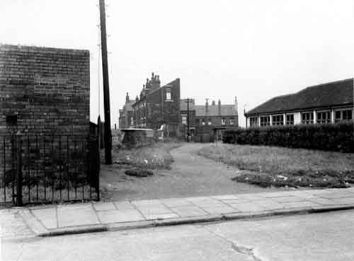 Part of a series taken above ground for Middleton Outfall Sewer in August 1953. Looking north-north-east from Derbyshire Street. On the right the side of Hunslet Nursery; to the left an electricity sub station. Between these, a telegraph pole and wall bordering a track with grass and hedge to the side of the nursery. A boy is playing on a second pole, with a girl standing next to him. Behind the wall is the front three-quarter view of a terrace of houses on Iveridge Street. Further houses are to the right and behind these, on Iveridge Mount and Place. In the foreground the street and pavement.