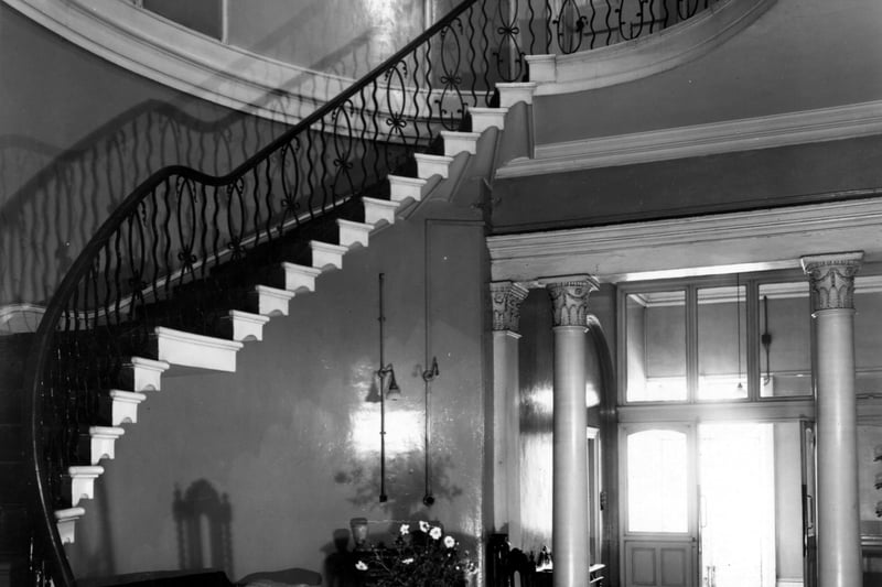 Inside Denison Hall, showing an entrance vestibule, cantilevered staircase with wrought iron balustrade. Decorated plaster columns, floor tiles, carpet and various items of furniture and ornaments. Pictured in September 1949.
