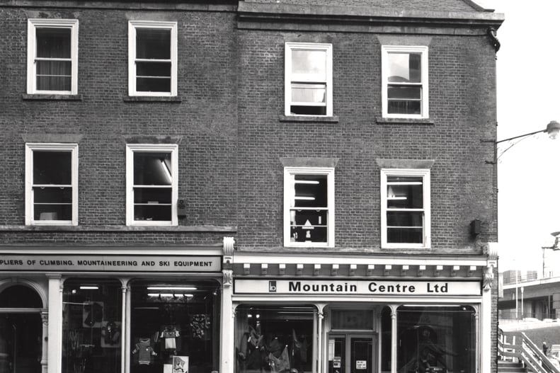 A photograph of Dean Street Newcastle upon Tyne taken in 1979. The view shows the two adjoining buildings which form the 'Mountain Centre Ltd' suppliers of climbing mountaineering and ski equipment. To the right of the Mountain Centre is a flight of stairs which leads upwards. 