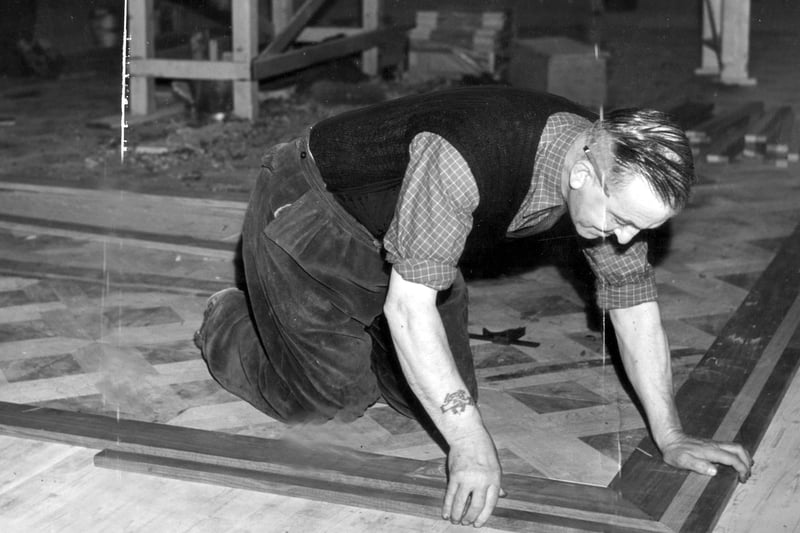 A craftsman fitting the new ballroom floor after a fire