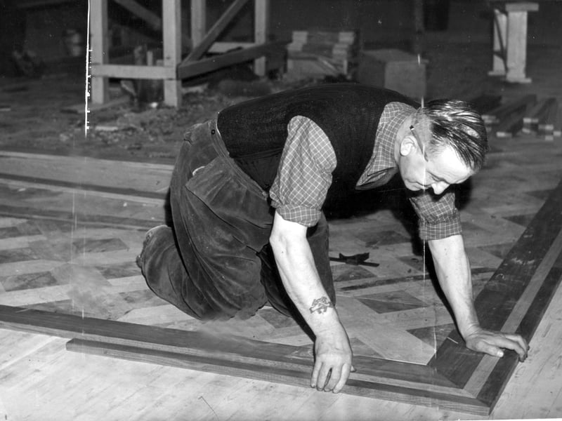 A craftsman fitting the new ballroom floor after a fire