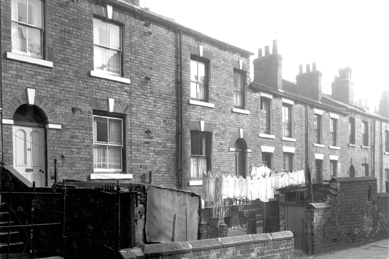 Odd numbered back-to-back houses on Lower Brunswick Street in September 1959.. Numbers run to the right in ascending order from number 23 on the left. Houses have basement entrances and walled yards where washing lines have been put up.