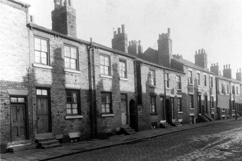 Back-to-back terraced houses on Derby Crescent . Between houses 49 and 51, 51 and 53, and 55 and 57 there are ginnels giving access to Derby Terrace at the rear of the buildings. Clothes are hung out on lines stretched across the street. Pictured in October 1958.
