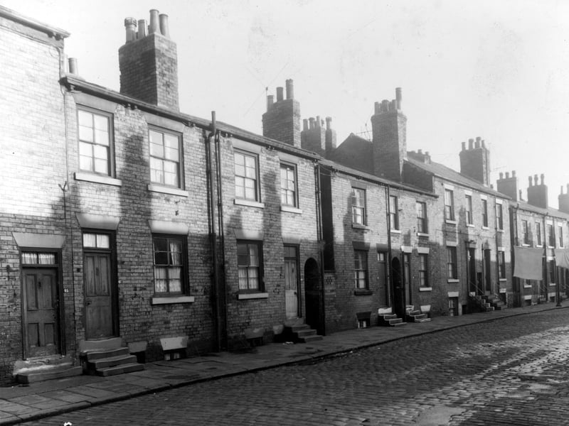 Back-to-back terraced houses on Derby Crescent . Between houses 49 and 51, 51 and 53, and 55 and 57 there are ginnels giving access to Derby Terrace at the rear of the buildings. Clothes are hung out on lines stretched across the street. Pictured in October 1958.