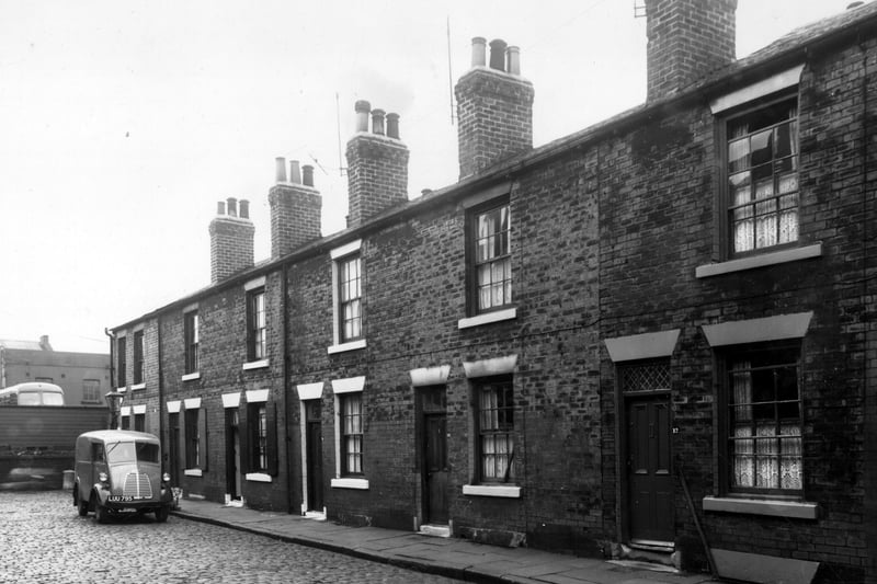  Single fronted back-to-back houses on Chambers Street, numbers run from 22 to 12, left to right. Across the wall on the left edge is a Leeds Corporation bus depot. A royal mail delivery van is parked outside number 20 Chambers Street. Pictured in October 1958.