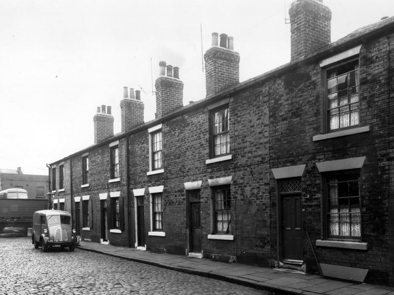  Single fronted back-to-back houses on Chambers Street, numbers run from 22 to 12, left to right. Across the wall on the left edge is a Leeds Corporation bus depot. A royal mail delivery van is parked outside number 20 Chambers Street. Pictured in October 1958.